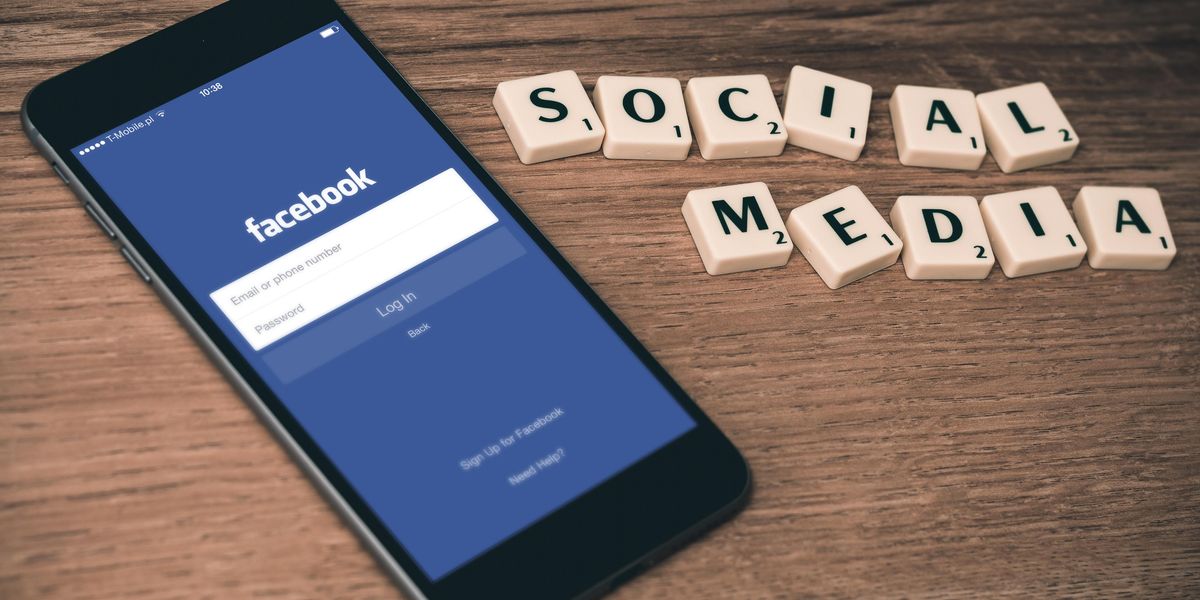 A Facebook applikációja egy telefonon "social media" felirat mellett, egy asztalon