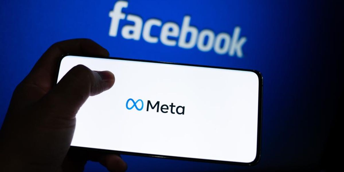 A Facebook logója előtt látható egy telefonon a közösségi oldal új neve, a Meta