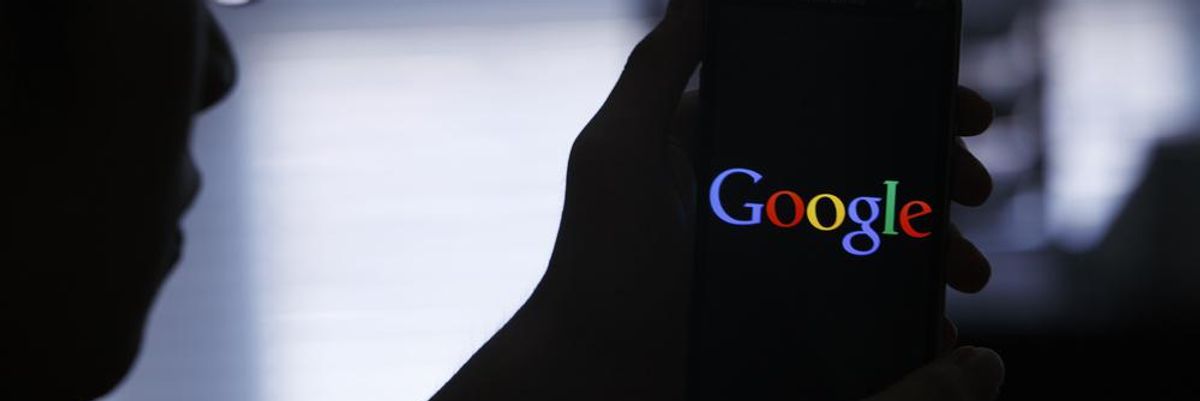 A gonosz pert megnyerő Google logója egy telefon képernyőjén, amelyet egy szemüveges ember tart a kezében, nagy a sötétség