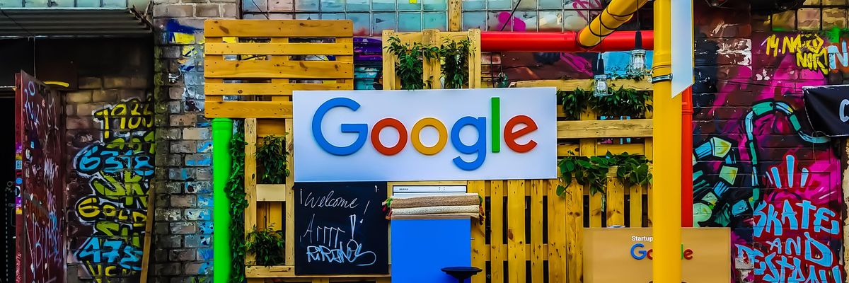 A Google logója színes raklapok és egy graffitis fal előtt