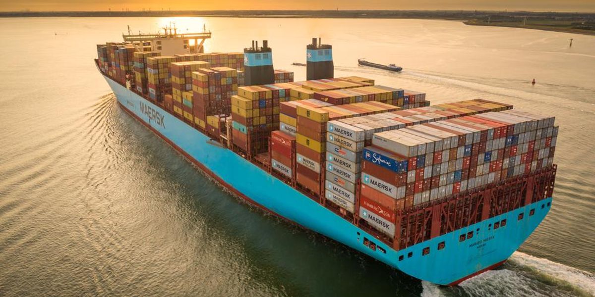 A Maersk konténerszállító társaság kék színű konténerhajója konténerekkel megpakolva szeli az óceán vizét naplementében