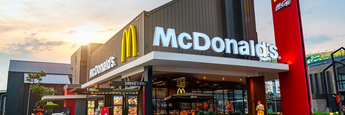 A McDonald's egyik étterme, a cég logója és felirata a homlokzaton, Ronald McDonald bohóc az étterem előtt van kirakva, és a McDrive-ban is áll egy autó