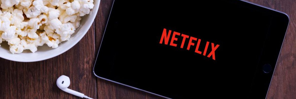 A Netflix logója egy tableten, mellette egy tál popcorn és egy fülhallgató