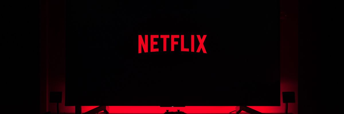 A Netflix logója látható egy okostévén, ami egy sötét szobában piros fényekkel van kivilágítva 