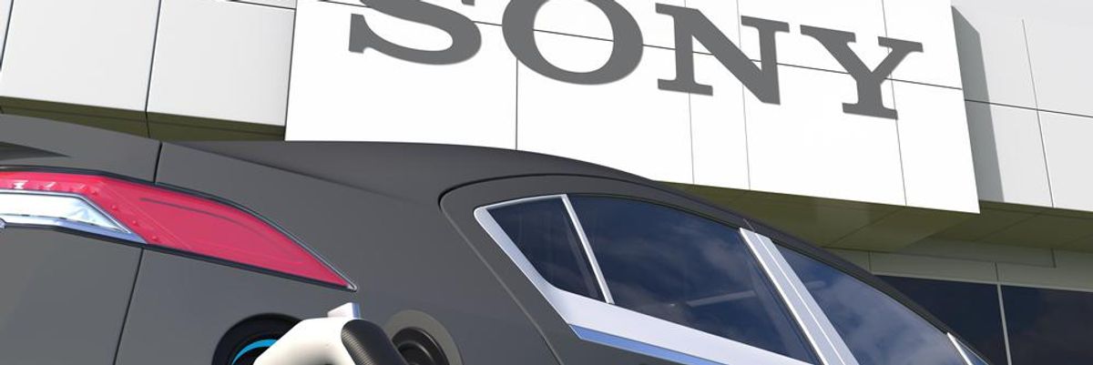 A Sony elektromos autója töltés közben a Sony épülete előtt, amelynek homlokzatán a Sony felirat látható