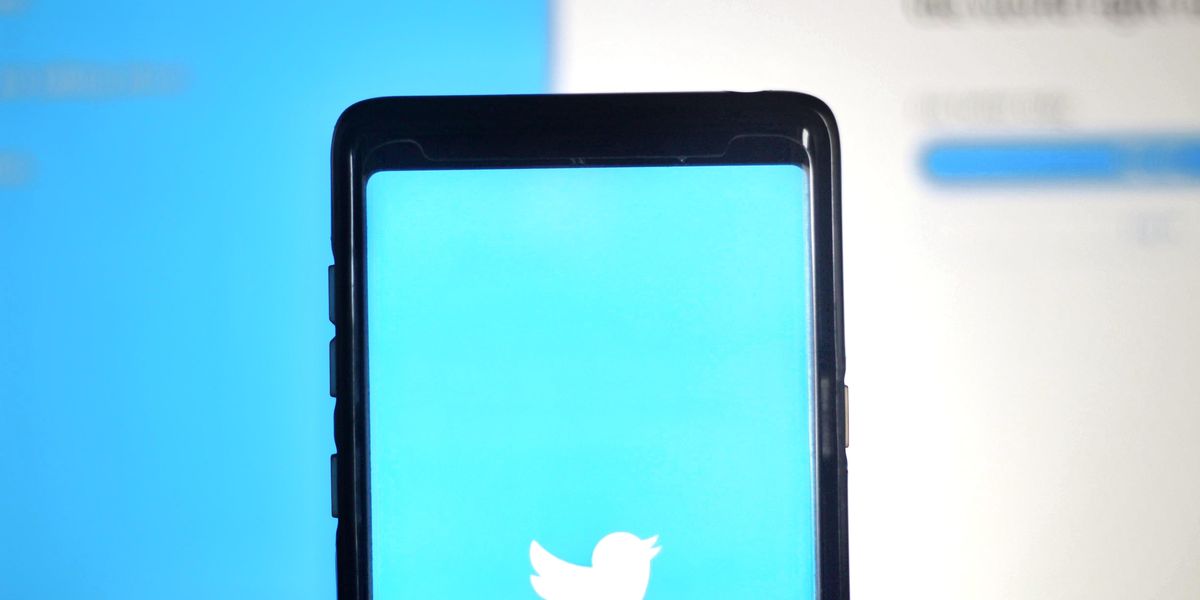 A Twitter logója, egy fehér madár kék háttérben látható egy okostelefon kijelzőjén 