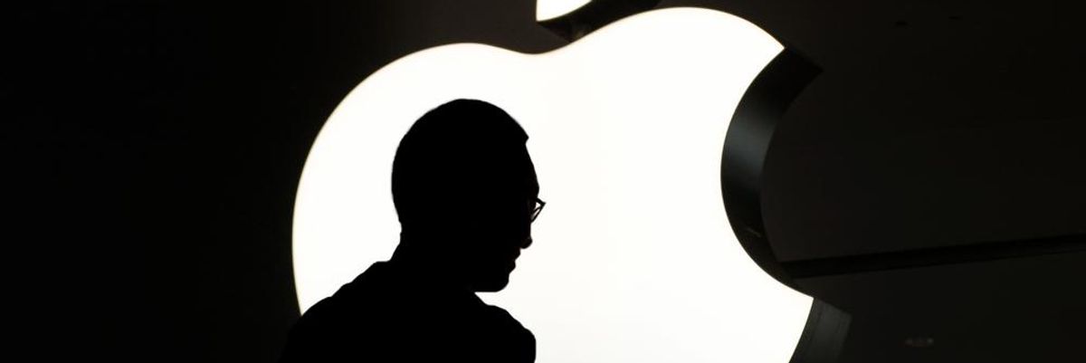 A világ legértékesebb vállalatának, az Apple-nek a logója, előtte egy munkavállaló telefonozik