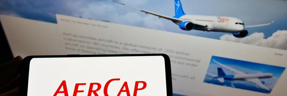 AerCap logó okostelefonon háttérben képernyő repülőgépekkel