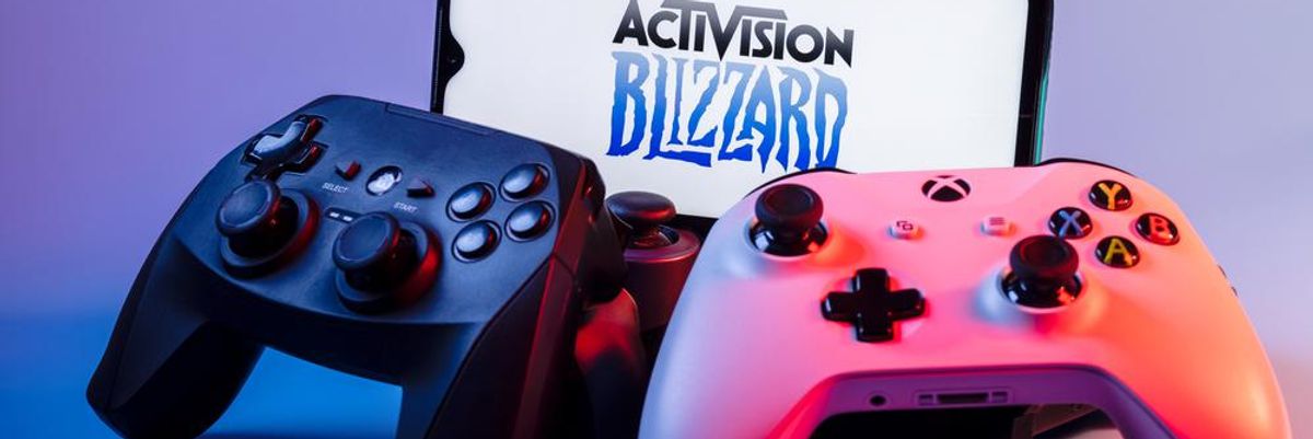 Az Activision Blizzard logója egy okostelefon képernyőjén, ami előtt két Xbox kontroller található
