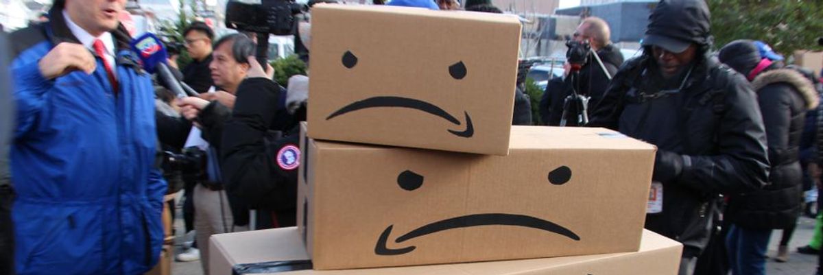 Az Amazon logója átalakítva egy dühös arccá egy tüntetésen, riporterek, tüntetők láthatók a háttérben
