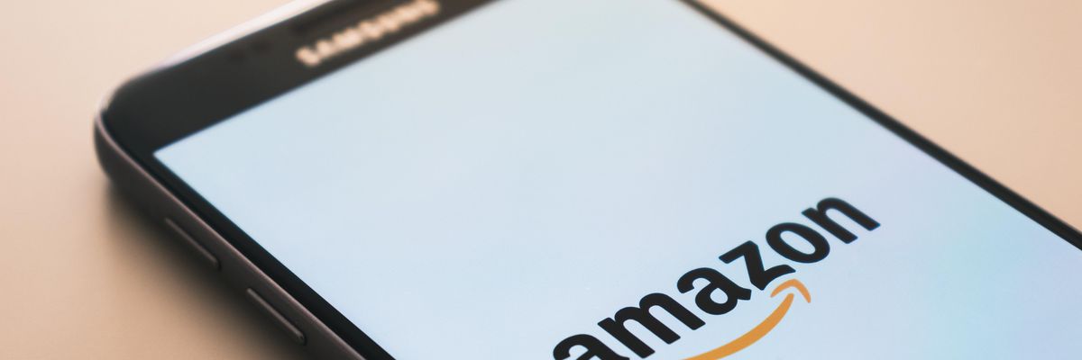 Az Amazon mobilos applikációjának logója egy okostelefonon ami egy faasztalra van letéve