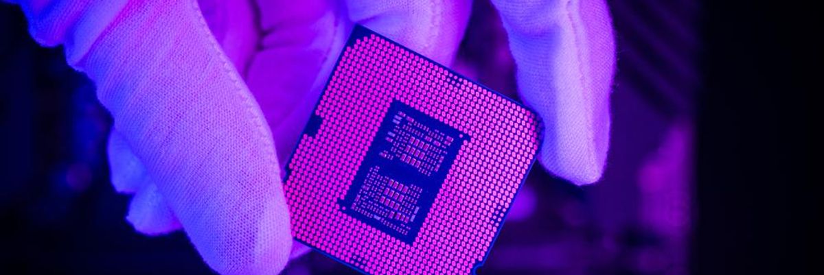Az Intel chipjét fogja a kezében egy fehér kesztyűs szakember egy lila környezetben