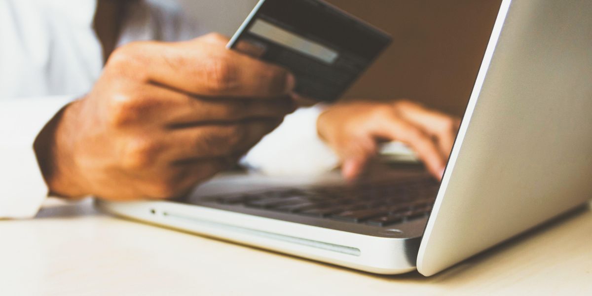 Bankkártyával, laptoppal online fizető ember keze