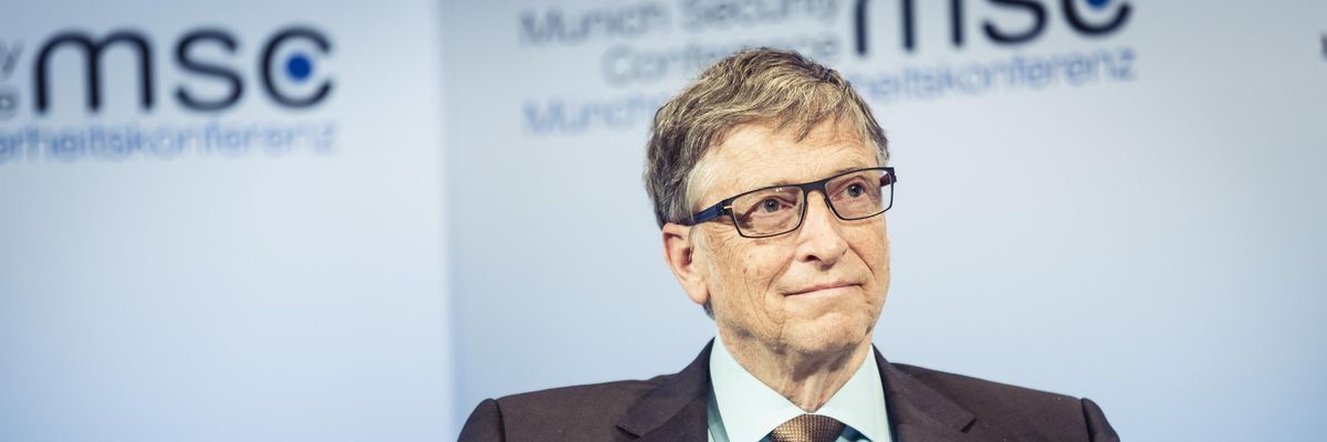 Bill Gates öltönyben ül egy székben és figyel