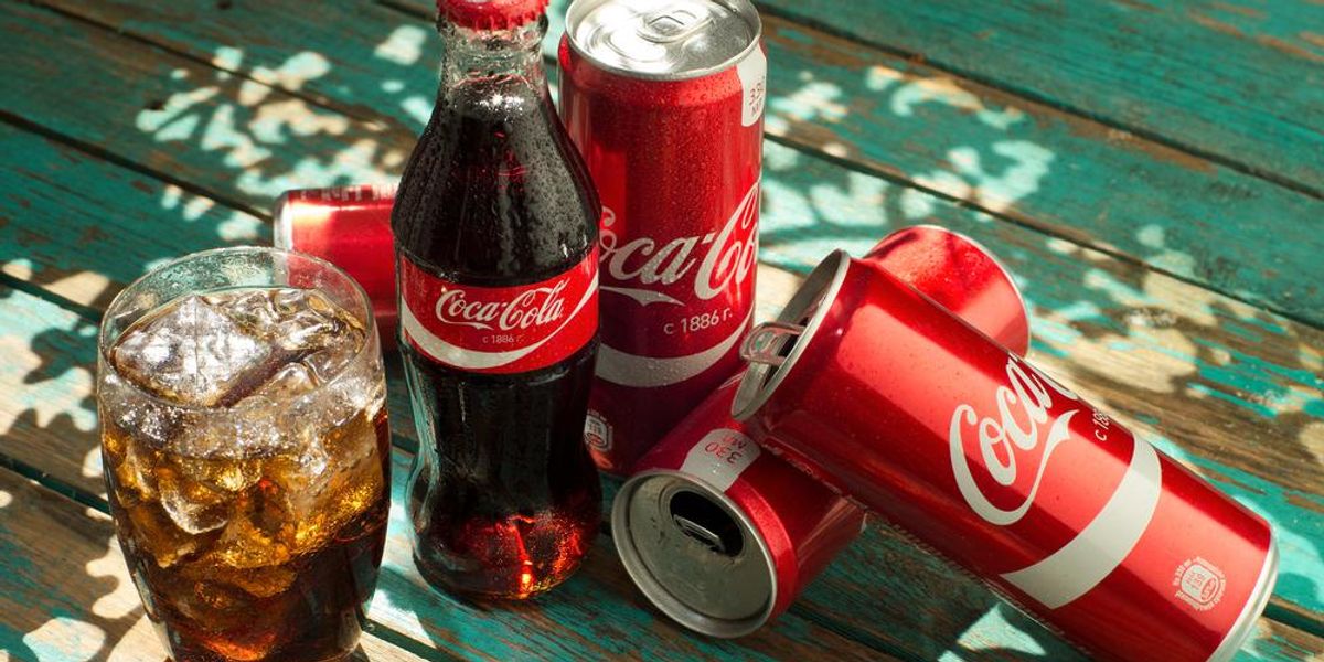 Coca-Colás üveg és dobozok, illetve egy pohár kóla egy kopott fafelületen