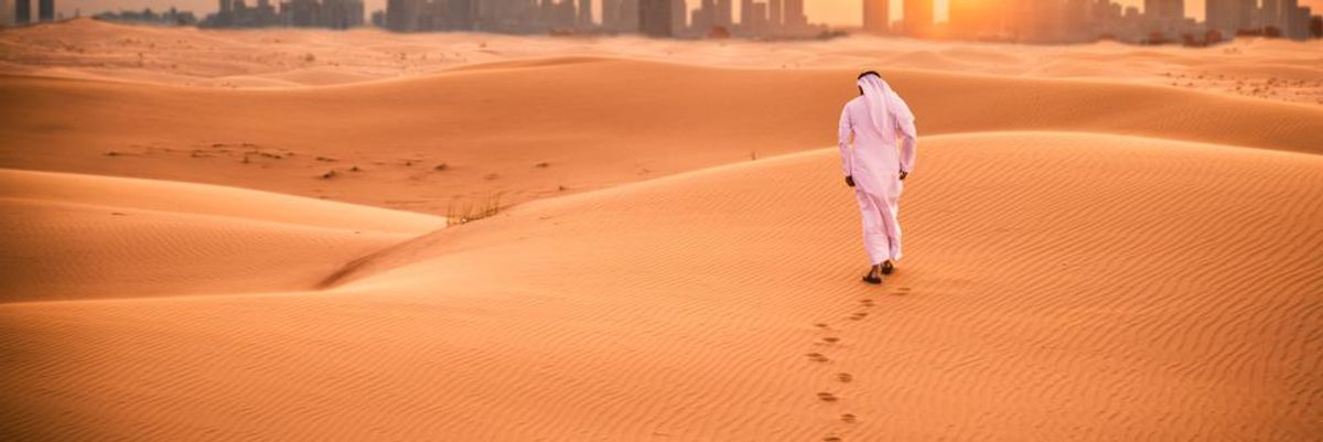 Csalódott arab ember fehér ruhában a sivatagban sétál az Egyesült Arab Emírségek, pontosabban Dubai felé, miután megtudta, hamarosan társasági adót kell fizetnie