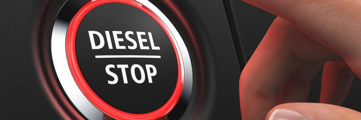 Diesel Stop felirat egy piros szegélyű gombon, amit épp megnyomni készül egy mber