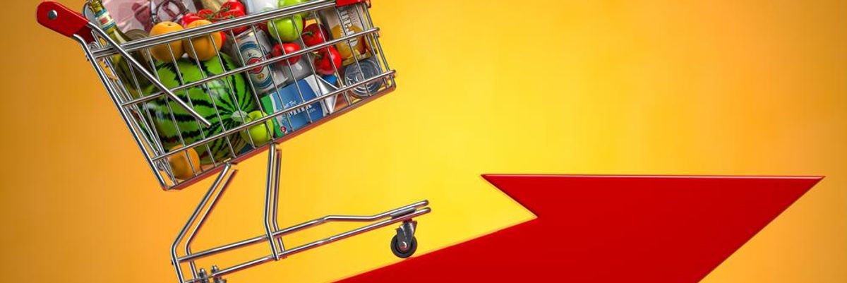 Dráguló termékeket szemléltető bevásárlókocsi az inflációt jelző piros nyílon, a kosárban óvszer, bébiétel, édesség és kávé is van