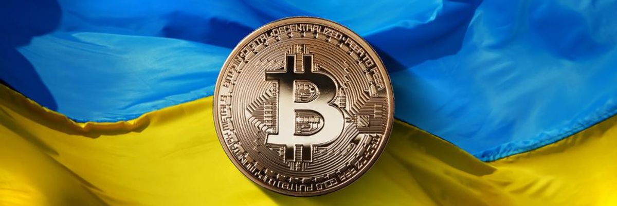 Egy bitcoin kriptovaluta tokenje az ukrán zászló előtt, kriptovalutákkal támogatják az ukránokat az orosz támadás alatt