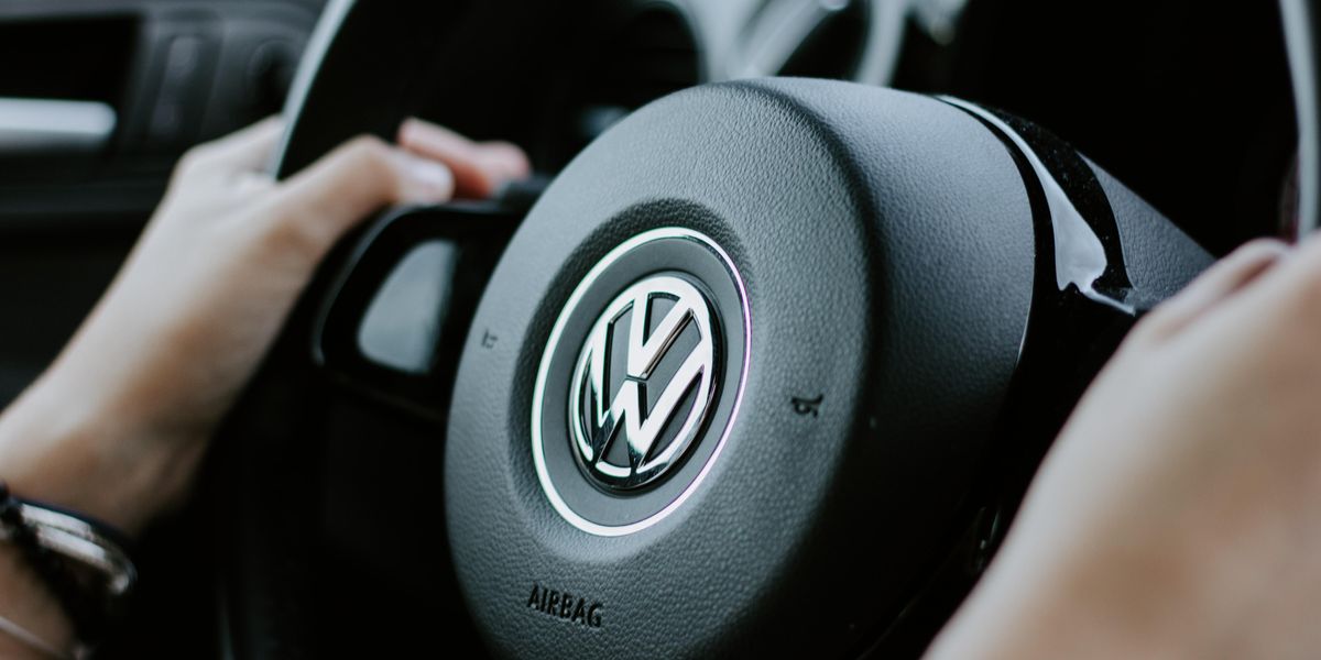 Egy ember két kézzel fogja a Volkswagen autójának a kormányát, amelyen a Volkswagen logója látható