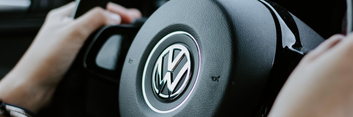 Egy ember két kézzel fogja a Volkswagen autójának a kormányát, amelyen a Volkswagen logója látható