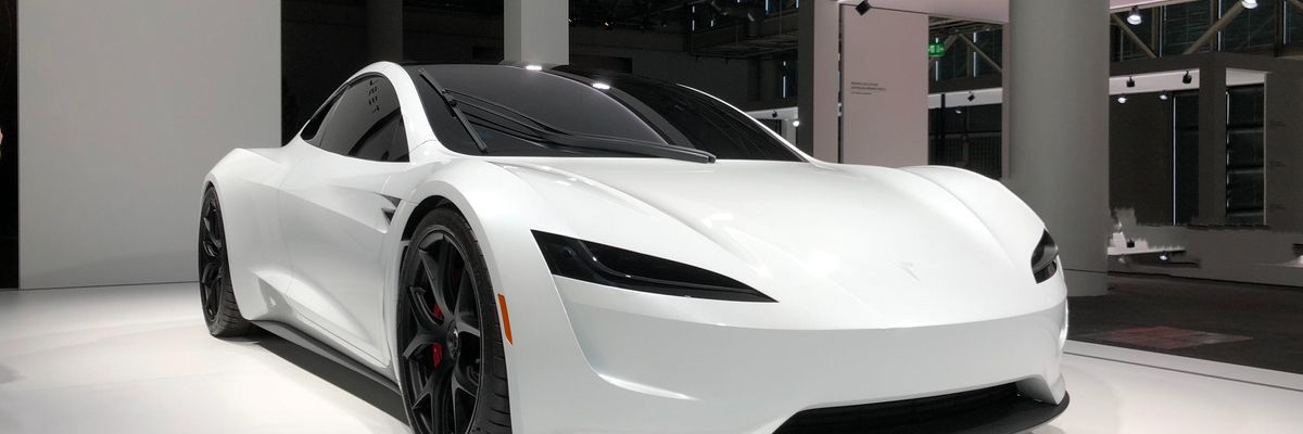 Egy fehér Tesla Roadster áll egy kiállításon a Tesla épületében