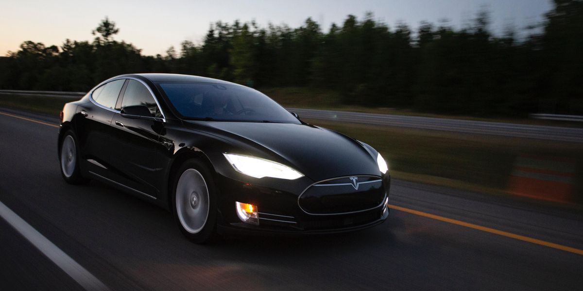 Egy fekete Tesla elektromos autó halad az autópályán a naplementében