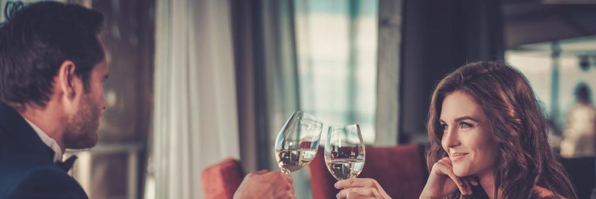 Egy férfi és egy nő borral koccint a randijukon, ami azért jött össze, mert feltüntették, hogy kriptovalutákkal kereskednek