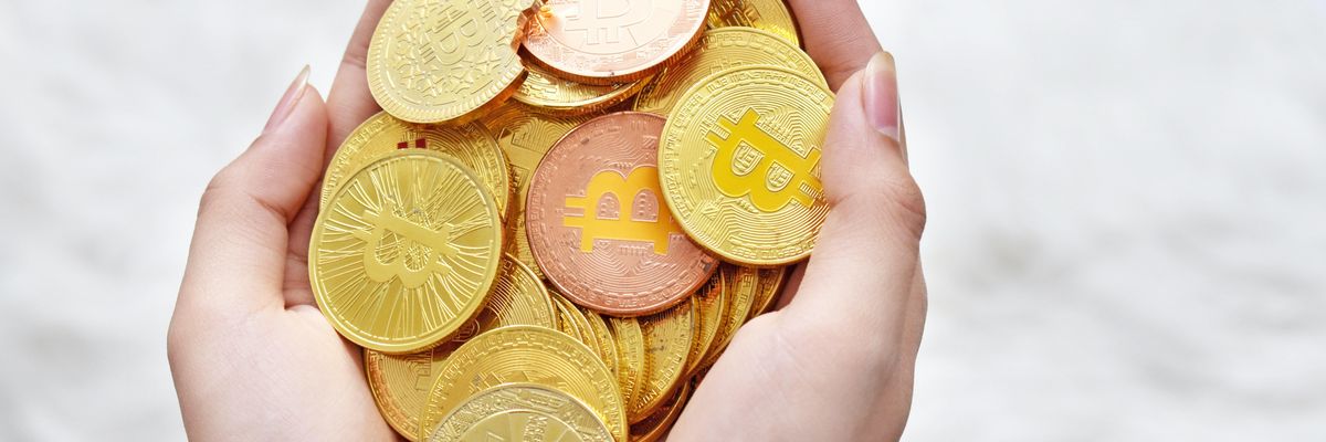 Egy hölgy egy maréknyi bitcoin érmét tart a kezében