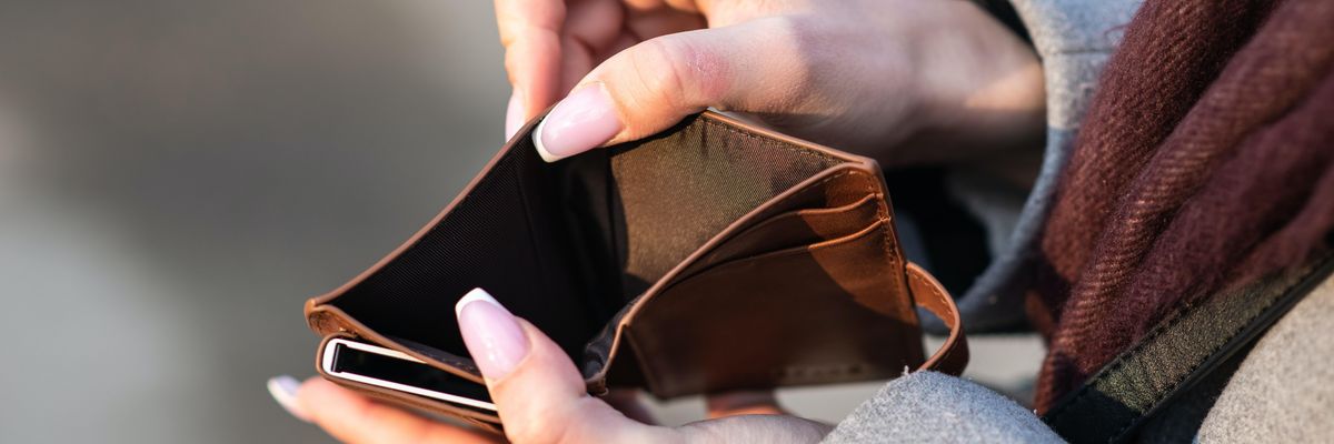Egy nő éppen azt mutogatja, hogy nincs pénz a pénztárcájában