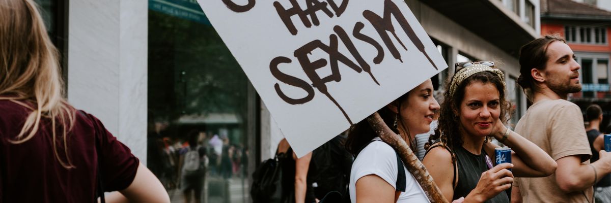 Egy nő szeximussal kapcsolatos táblát tart egy tüntetésen