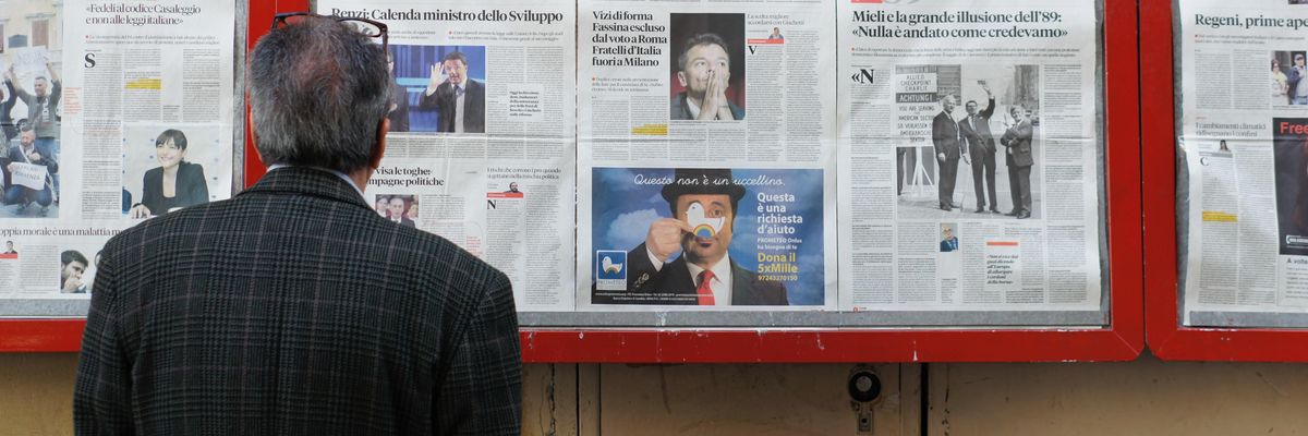 Egy öltönyös férfi olvassa a híreket különböző újságokból egyszerre