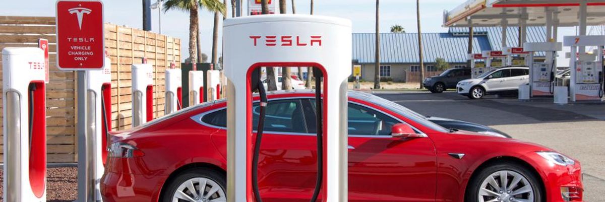 Egy piros színű Tesla töltődig a Tesla Supercharger töltőállomásán, a vállalat anyagilag támogatja ukrán dolgozóit