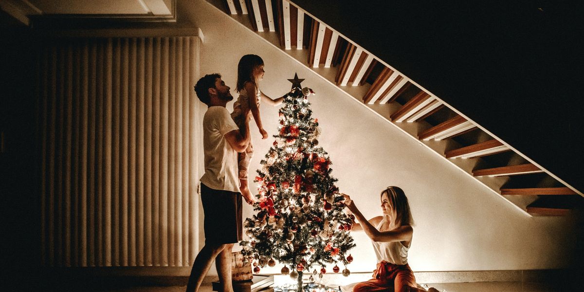 Egy szép csald díszíti a karácsonyfát karácsonykor a lépcső alatt