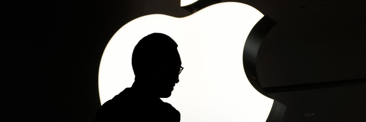 Egy telefonozó ember sziluettje látható háttérben az Apple logójával
