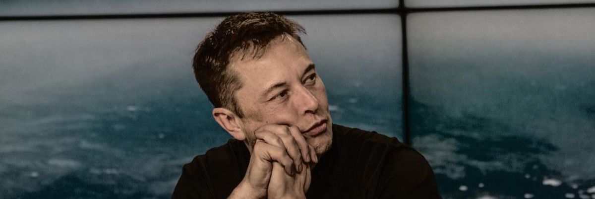 Elon Musk fekete pólóban egy asztalnál, mikrofon előtt töri a fejét, hogyan nyerje meg a SolarCity pert