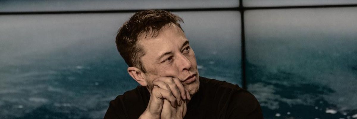 Elon Musk fekete pólóban egy mikrofon előtt ülve nézi a abeszégetőpartnerét