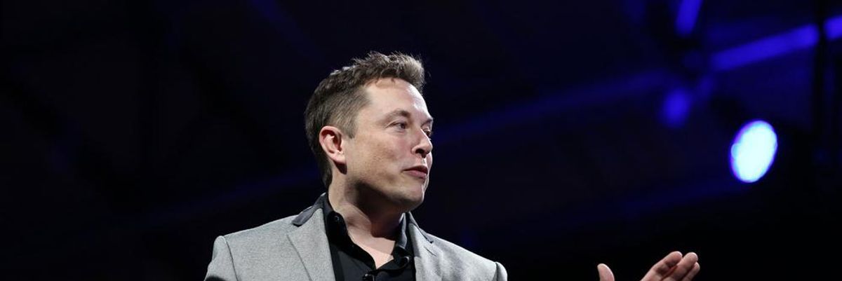 Elon Musk szürke zakóban, fekete ingben magyaráz testvérének, Kimbal Musknak valamit