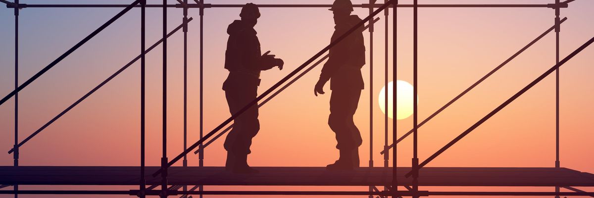 Építőmunkások az állványon a felkelő Nap fényében