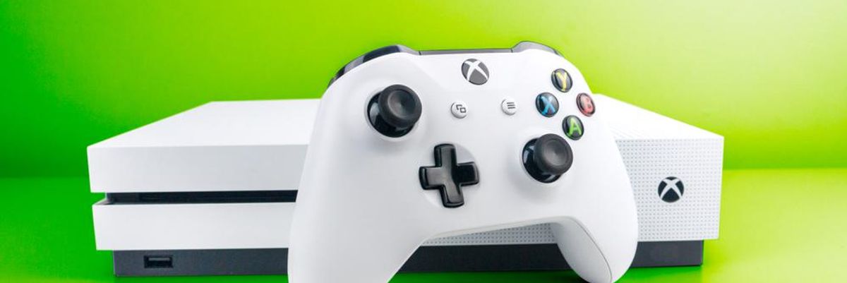 Fehér színű Xbox One konzol és a hozzá tartozó joystick egy neonzöld környezetben