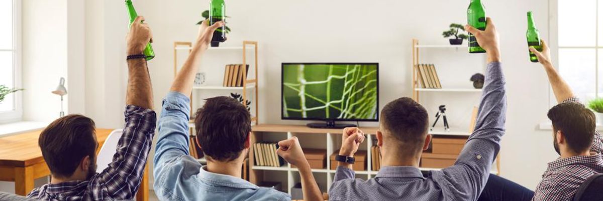 Fiatal férfiak meccset néznek a nappaliban sörrel