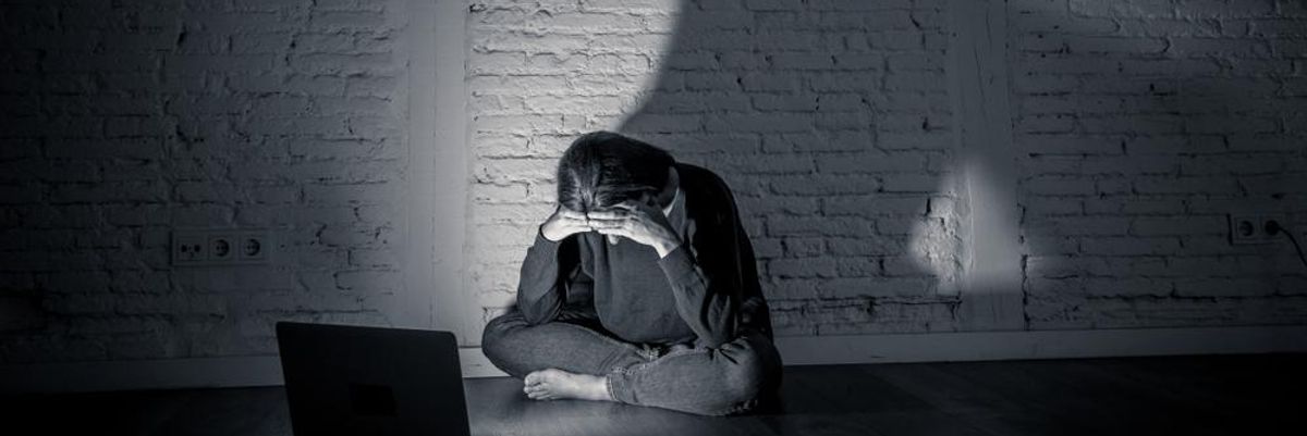 Fiatal lány egy sötét szobában szomorkodik a laptopja előtt ülve, miután gyűlöletbeszéd célpontjává vált