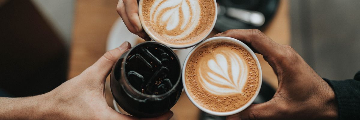 Három ember kávéval koccint a mesterképzés végén