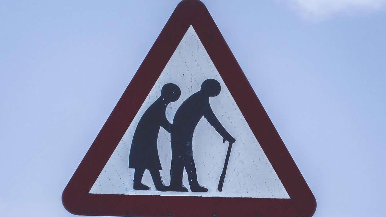 Idős emberek egy figyelmeztető úttáblán.