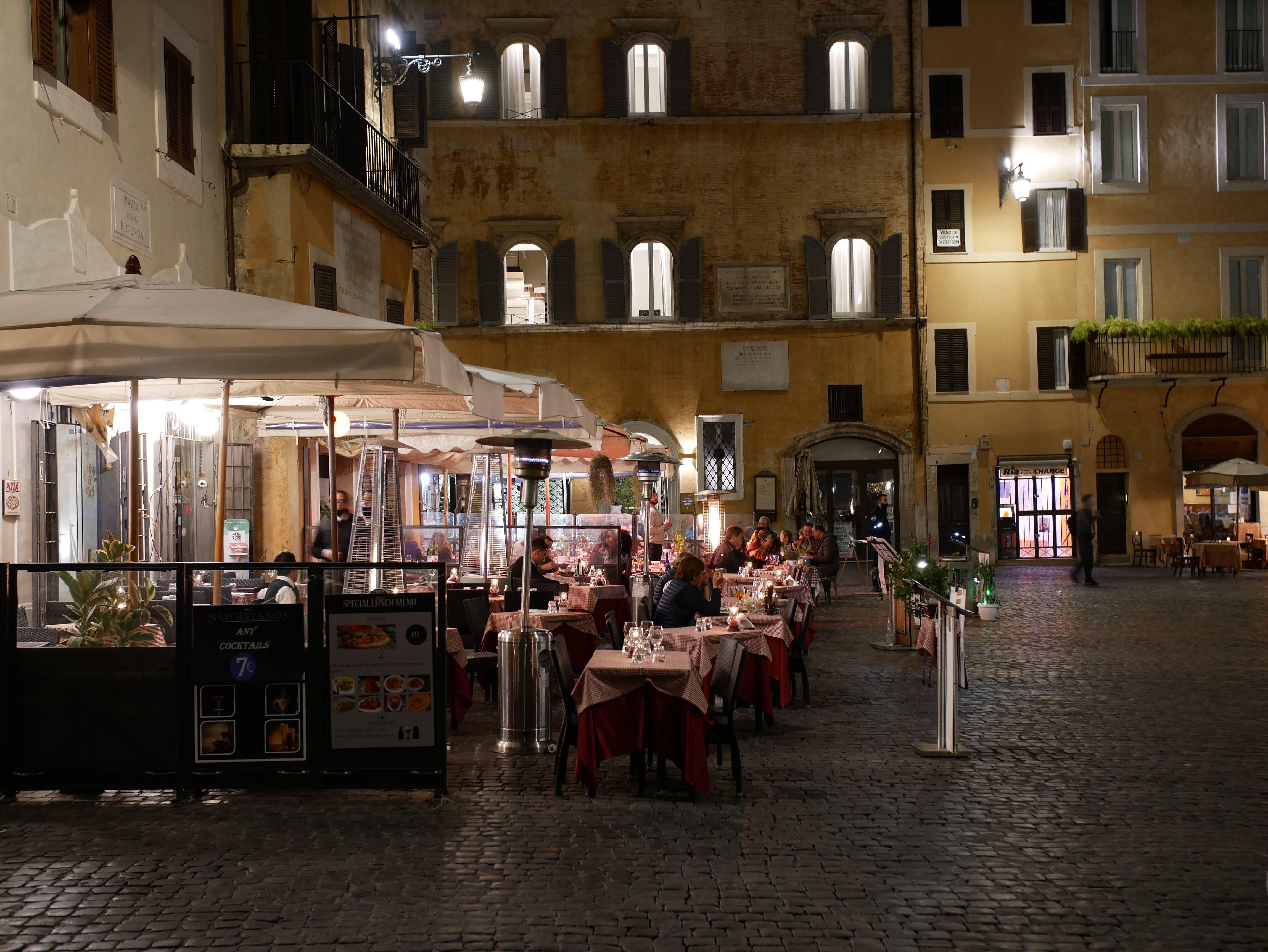 Étterem terasza este egy vársoi téren vendégekkel