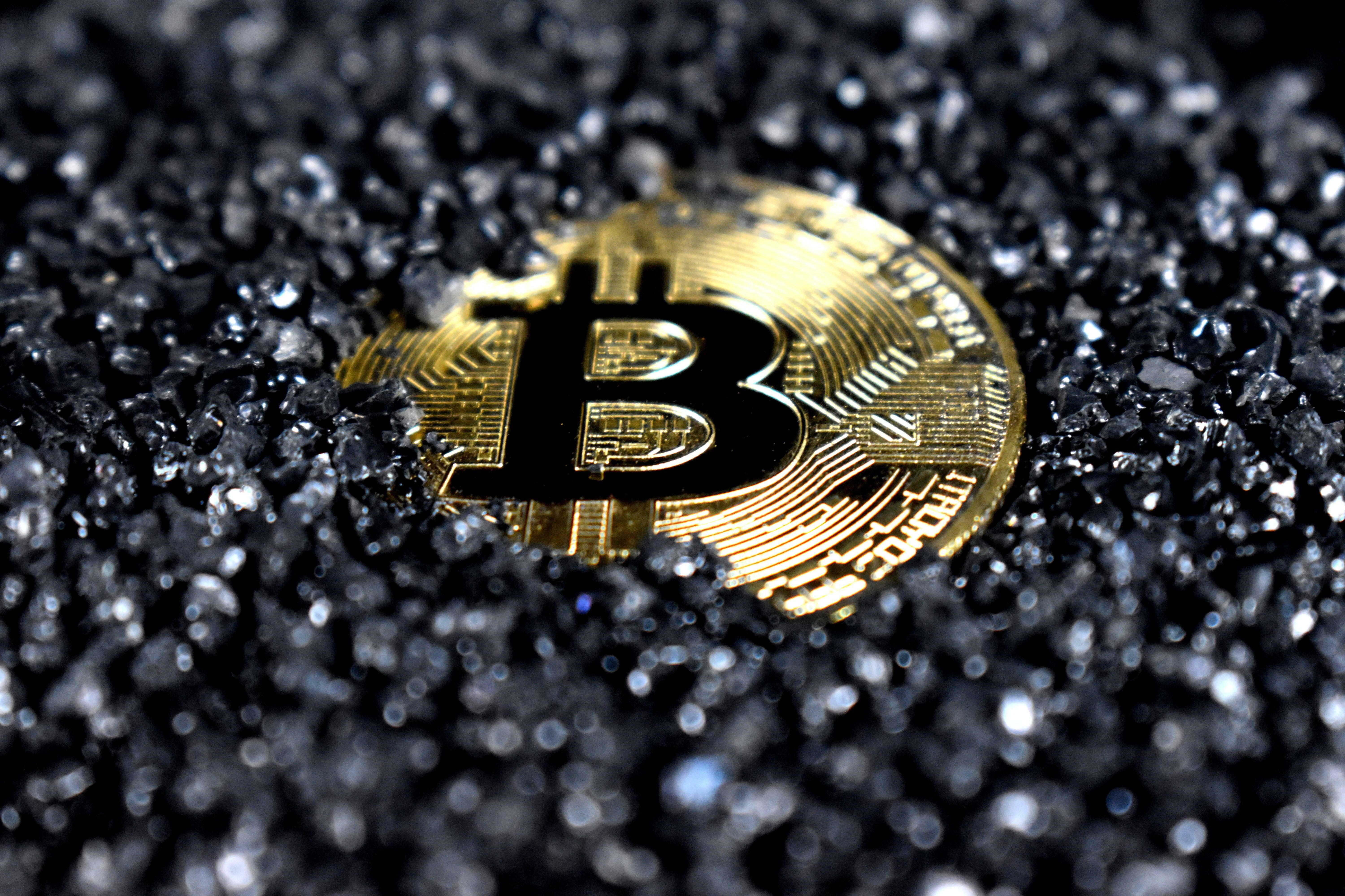 Bitcoin érme fekete kristályokkal félig betemetve
