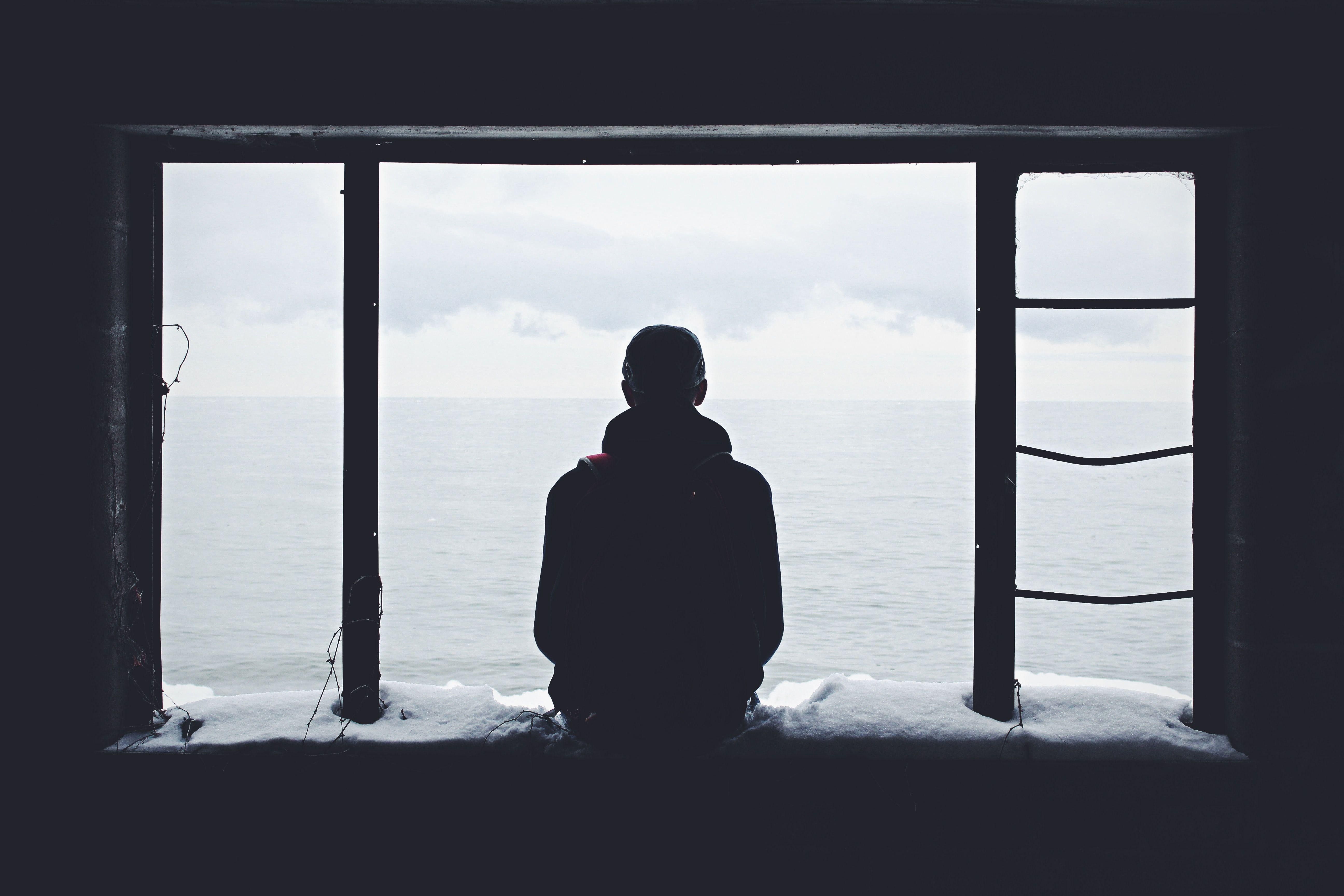 Magányos férfi ül egy behavazott ablakban a tengert bámulva