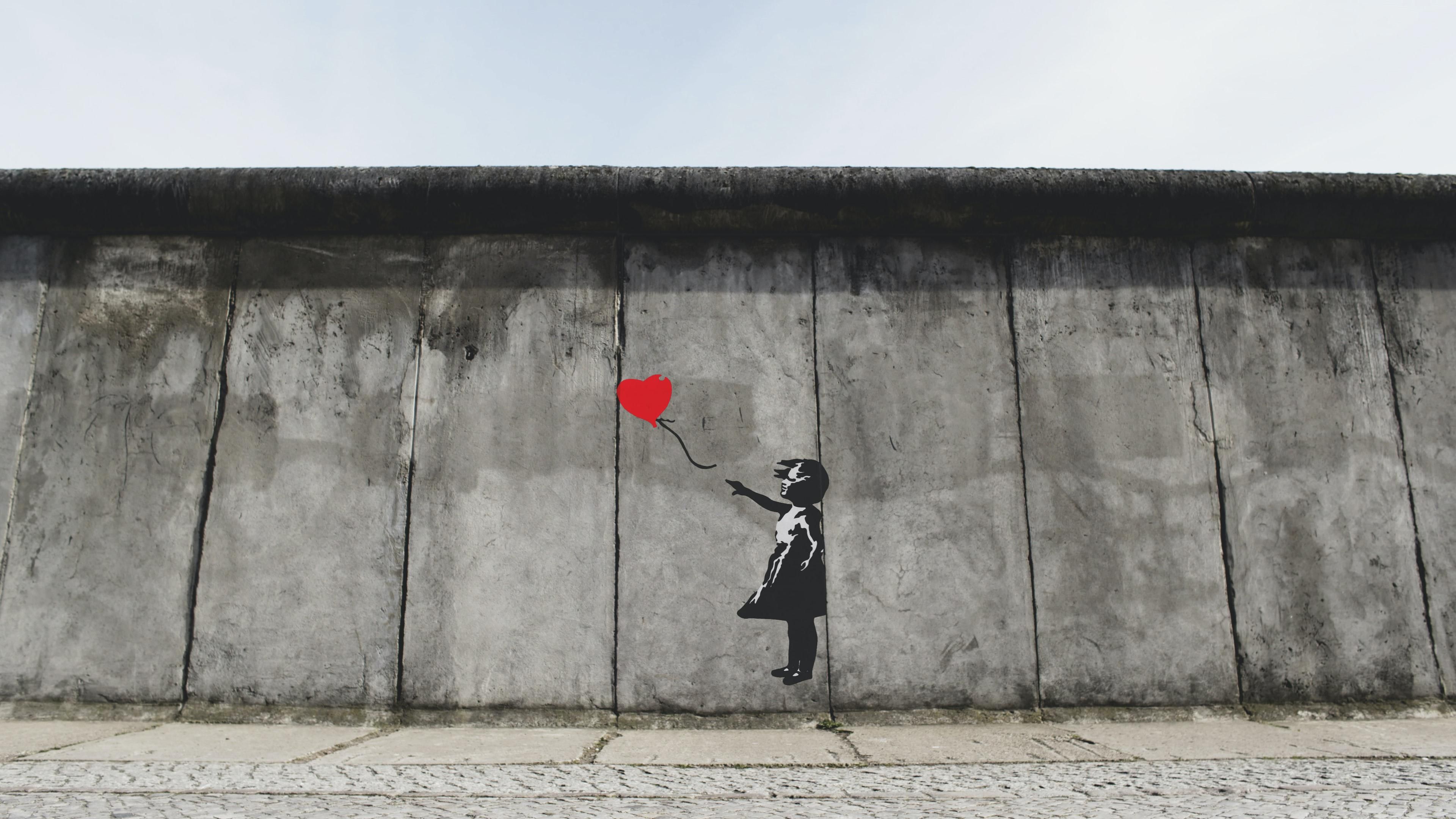 Banksy "Ballon Girl" alkotása egy falon, borongós időben