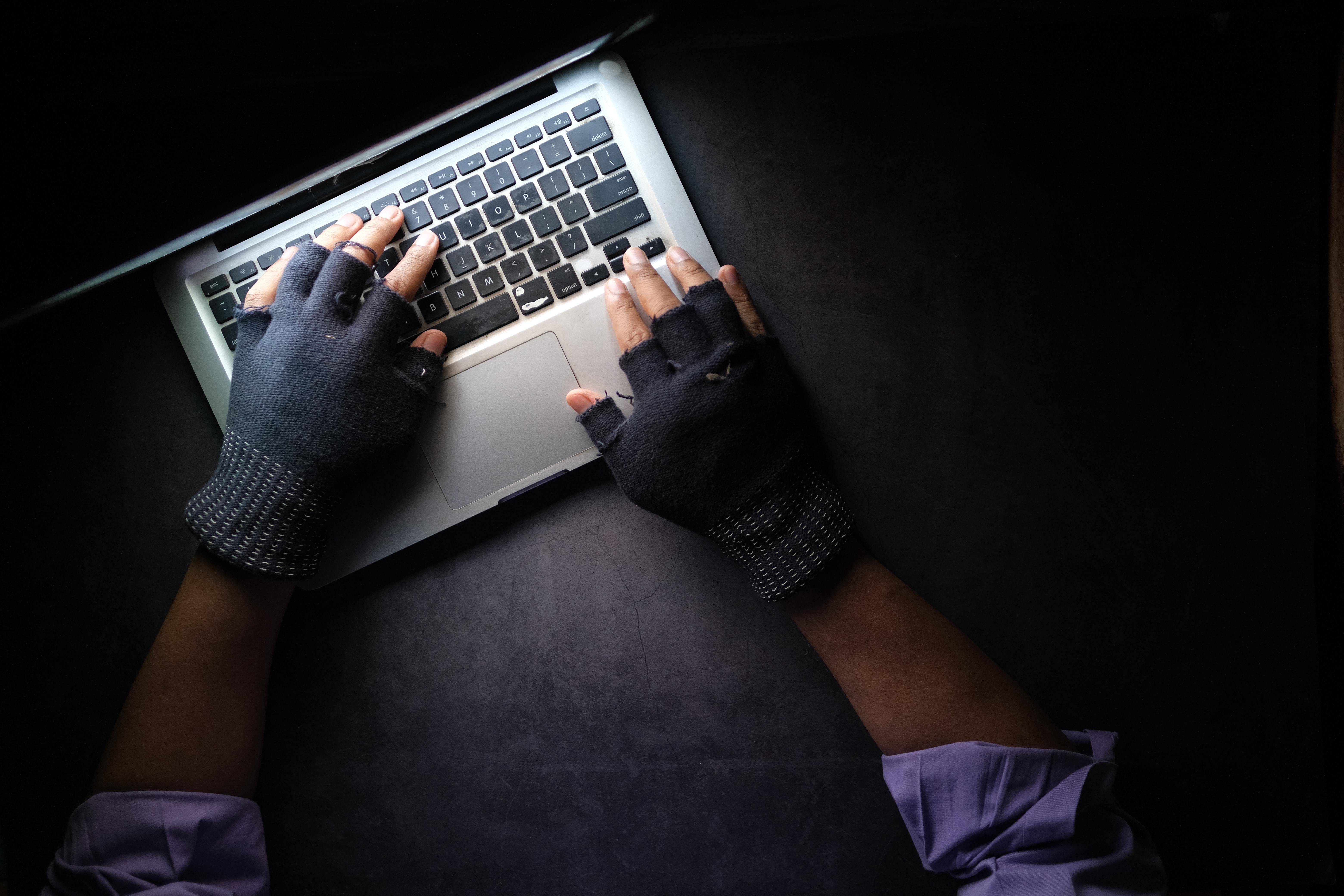 Online csaló sötét szobában bűnöző kesztyűvel készíti a járványhoz köthető átverését