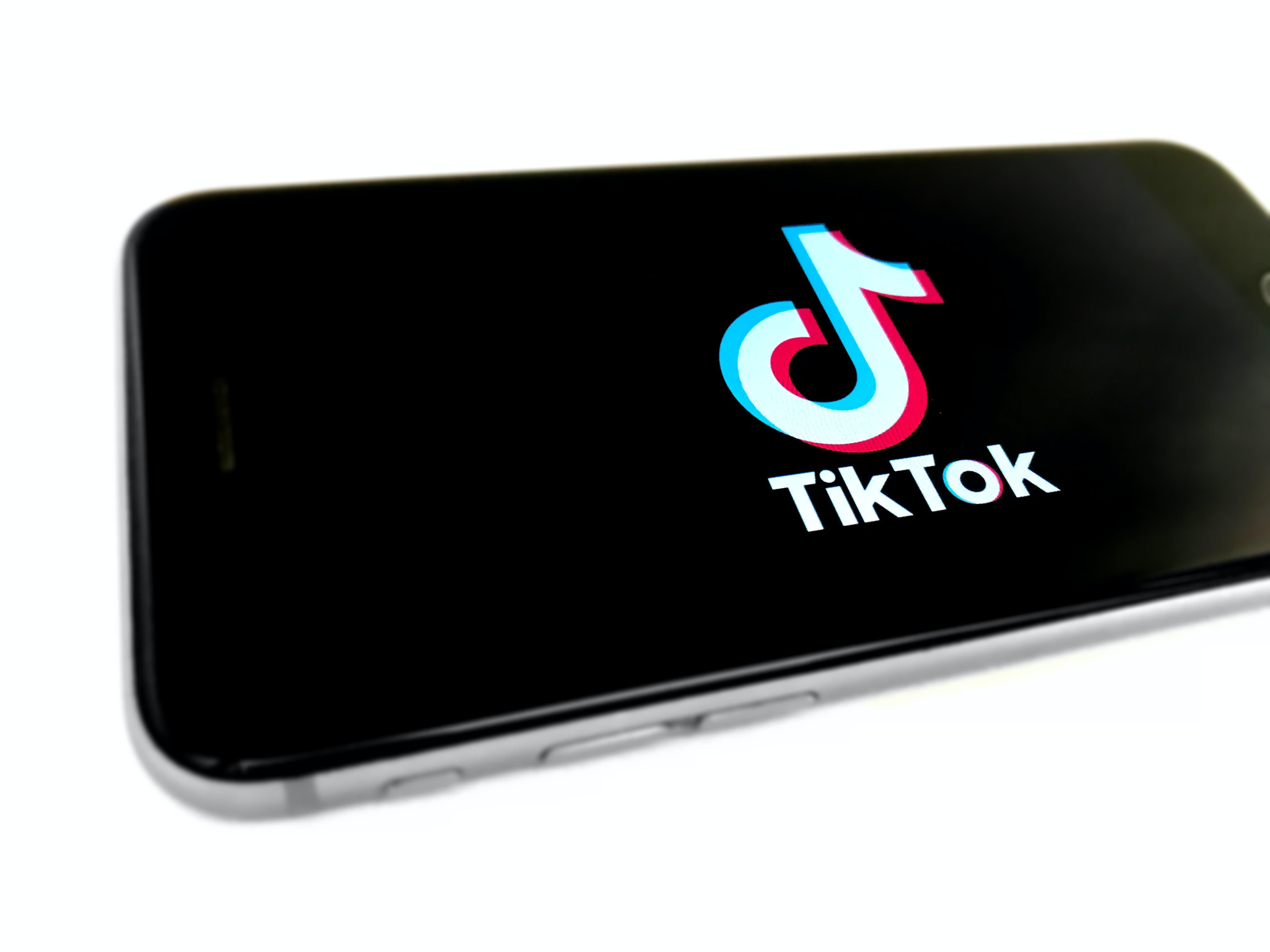 TikTok logó egy okostelefonon, fehér háttérrel